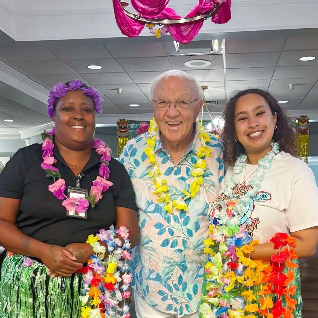 Member with employees holding colorful Leis